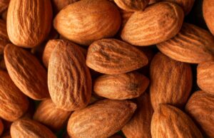 The Daily Handful: Scientists Reveal the Triple Impact of Almonds on Health handful of raw almonds on a wooden table