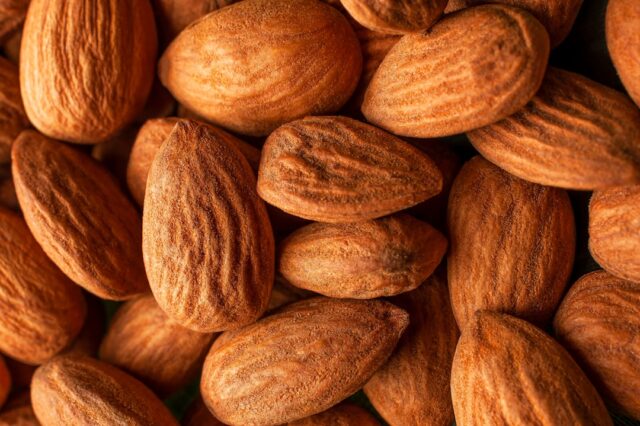 the-daily-handful-scientists-reveal-the-triple-impact-of-almonds-on-health-image handful of raw almonds on a wooden table