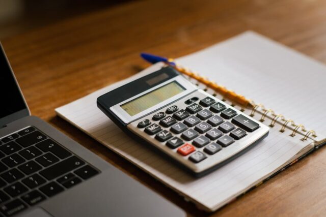 travel insurance cost calculator with laptop and calculator on desk