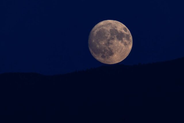 Blue Micromoon rising over dark horizon at lunar apogee